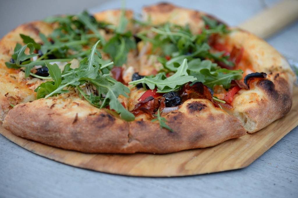 Pizza met rucola, olijven en geroosterde paprika